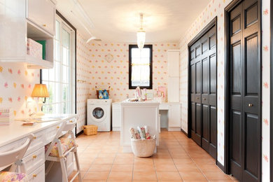Modelo de lavadero multiusos tradicional con armarios con paneles empotrados, puertas de armario blancas, paredes multicolor, suelo de baldosas de terracota, suelo naranja y encimeras blancas