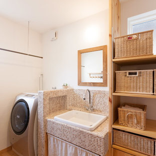 Réalisation d'une buanderie asiatique avec un placard sans porte, un mur blanc, un sol en bois brun et un sol marron.