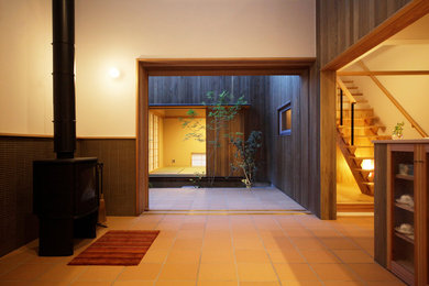 Idee per un soggiorno etnico con pareti bianche, pavimento in terracotta, camino bifacciale e pavimento marrone