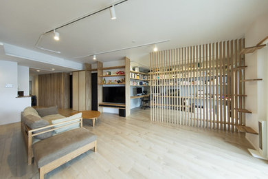 Ejemplo de salón abierto moderno sin chimenea con paredes blancas, suelo de madera clara y pared multimedia