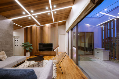Cette image montre un salon minimaliste ouvert avec un mur multicolore, un sol en bois brun et un sol marron.