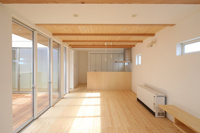 Imagen de salón abierto de tamaño medio con paredes blancas, suelo de madera clara, televisor independiente y suelo beige