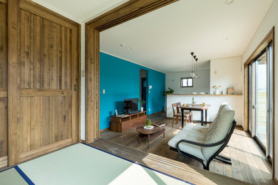 Diseño de salón asiático con paredes azules, suelo de madera en tonos medios, televisor independiente y suelo marrón