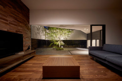 Стильный дизайн: маленькая парадная, открытая гостиная комната в стиле модернизм с коричневыми стенами, полом из фанеры, отдельно стоящим телевизором и коричневым полом для на участке и в саду - последний тренд