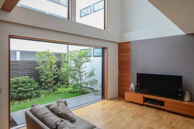 Foto de salón de estilo zen con paredes grises, suelo de madera en tonos medios, televisor independiente y suelo marrón