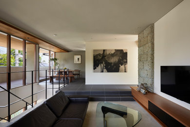 他の地域にあるコンテンポラリースタイルのおしゃれな独立型リビング (白い壁、磁器タイルの床、グレーの床、壁掛け型テレビ) の写真