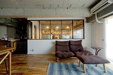 Cette image montre un salon urbain ouvert avec un mur blanc, un sol en bois brun, aucune cheminée, aucun téléviseur et un sol marron.