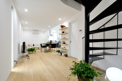 Diseño de salón abierto minimalista sin chimenea con paredes blancas, suelo de madera clara, televisor independiente y suelo blanco