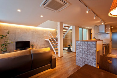 Modelo de salón de estilo zen con paredes beige, suelo de madera en tonos medios, televisor independiente y suelo marrón