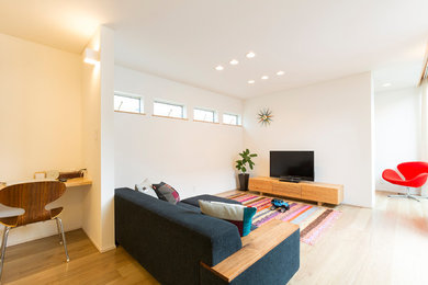 Imagen de salón contemporáneo con paredes blancas, suelo de madera clara, televisor independiente y suelo marrón