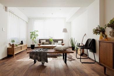 Cette photo montre un salon tendance avec un mur blanc, un sol en bois brun et un sol marron.