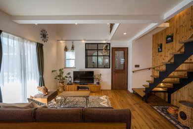 Modelo de salón abierto de estilo de casa de campo de tamaño medio con paredes multicolor, suelo de madera en tonos medios, televisor independiente y suelo marrón