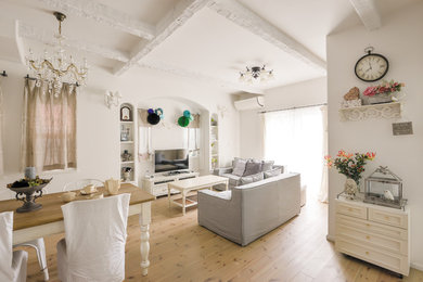 This is an example of a shabby-chic style living room in Other with medium hardwood flooring, white walls, a freestanding tv and beige floors.