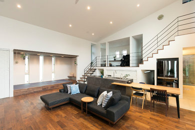 Diseño de salón moderno con paredes blancas, suelo de madera en tonos medios y suelo marrón