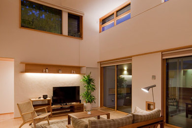 Modelo de salón abierto nórdico grande con paredes blancas, suelo de madera clara, televisor independiente y suelo marrón