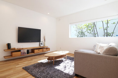 Modelo de salón abierto minimalista de tamaño medio sin chimenea con paredes blancas, suelo de madera en tonos medios, televisor colgado en la pared y suelo beige