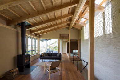 Modelo de salón abierto asiático con paredes beige, estufa de leña, suelo marrón y suelo de madera en tonos medios