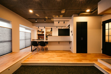 Modelo de salón abierto urbano de tamaño medio con paredes beige, suelo de madera clara, televisor colgado en la pared y papel pintado