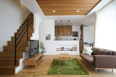 Modelo de salón abierto escandinavo sin chimenea con paredes blancas, suelo de madera en tonos medios, televisor independiente y suelo beige