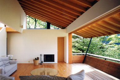 Offenes Nordisches Wohnzimmer mit beiger Wandfarbe, braunem Holzboden, Kamin, Kaminumrandung aus Holz und braunem Boden in Tokio