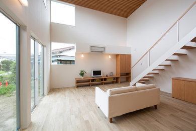 Diseño de salón asiático con paredes blancas, suelo de madera pintada, televisor independiente y suelo marrón