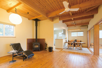 Exemple d'un salon asiatique ouvert avec un mur blanc, un sol en bois brun, un poêle à bois, un manteau de cheminée en brique et un sol marron.