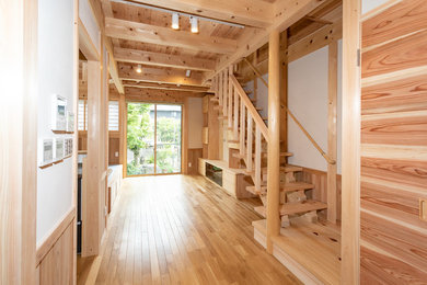 Diseño de salón abierto de tamaño medio con paredes blancas, suelo de madera en tonos medios, televisor colgado en la pared y suelo marrón