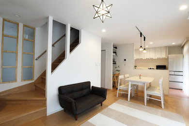 Foto de salón abierto moderno de tamaño medio sin chimenea con paredes blancas, suelo de contrachapado, televisor independiente y suelo beige