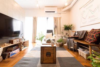 Modernes Wohnzimmer mit weißer Wandfarbe, braunem Holzboden, freistehendem TV und braunem Boden in Tokio