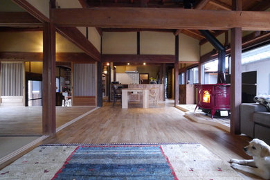 Ejemplo de salón abierto asiático con paredes beige, suelo de madera clara, estufa de leña y marco de chimenea de baldosas y/o azulejos