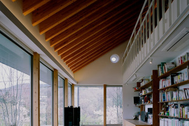 Diseño de biblioteca en casa abierta moderna de tamaño medio sin chimenea con paredes blancas, suelo de madera en tonos medios, televisor retractable y suelo marrón