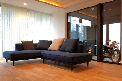 Diseño de salón abierto moderno de tamaño medio con paredes blancas y suelo de madera clara
