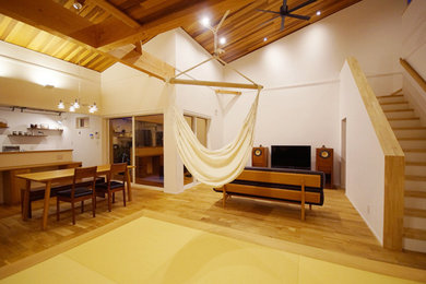 Modelo de salón abierto moderno con paredes blancas, suelo de madera en tonos medios, televisor independiente y suelo beige