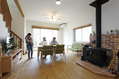 На фото: открытая гостиная комната в стиле кантри с паркетным полом среднего тона, печью-буржуйкой и фасадом камина из кирпича с