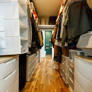 Immagine di una cabina armadio unisex industriale di medie dimensioni con nessun'anta, ante bianche, pavimento in legno massello medio, pavimento marrone e soffitto in carta da parati