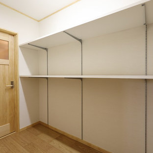 Foto di una grande cabina armadio etnica con pavimento in compensato e pavimento beige