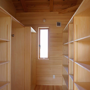 Ispirazione per una grande cabina armadio etnica con ante in legno chiaro e parquet chiaro