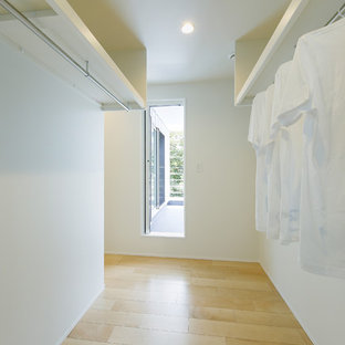 Exempel på ett litet skandinaviskt walk-in-closet för könsneutrala, med öppna hyllor, vita skåp, ljust trägolv och brunt golv