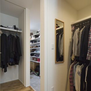 Imagen de armario vestidor unisex y papel pintado, moderno, de tamaño medio, con armarios abiertos, puertas de armario blancas, suelo de madera clara, suelo marrón y papel pintado
