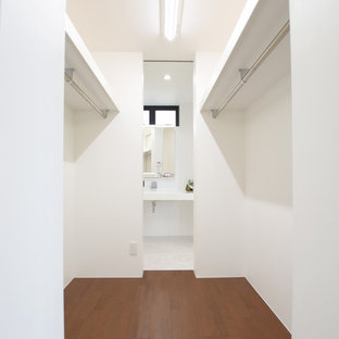 Esempio di una cabina armadio unisex moderna con pavimento in compensato e pavimento marrone