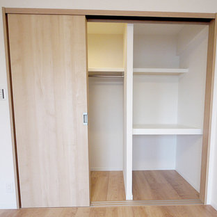 Foto di una cabina armadio nordica con ante in legno chiaro, parquet chiaro e pavimento beige