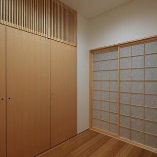 Foto de armario vestidor unisex, asiático, de tamaño medio, con armarios con paneles lisos, puertas de armario beige, suelo de madera en tonos medios y suelo marrón