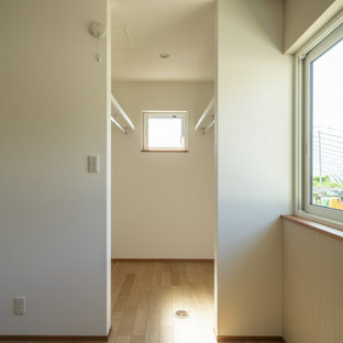 Ispirazione per una cabina armadio etnica di medie dimensioni con ante beige, parquet chiaro e pavimento beige