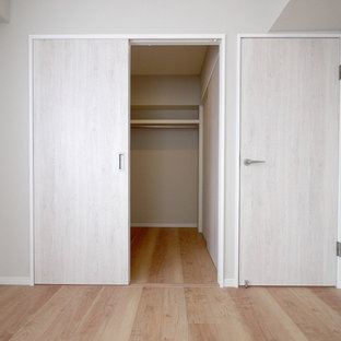 Immagine di una cabina armadio stile shabby con pavimento in compensato e pavimento beige