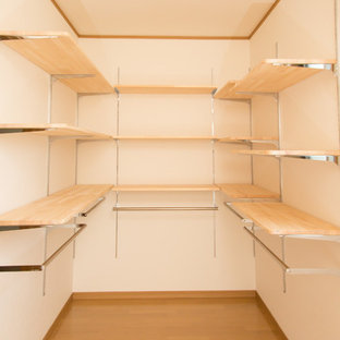 Foto di una cabina armadio unisex etnica di medie dimensioni con nessun'anta, ante in legno chiaro, pavimento in legno massello medio e pavimento marrone