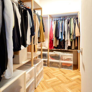 Esempio di una piccola cabina armadio unisex etnica con ante in legno chiaro, pavimento in compensato, pavimento marrone e soffitto in perlinato