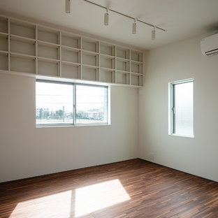 Cette image montre une chambre de fille minimaliste avec un mur blanc, un sol en contreplaqué et un sol marron.