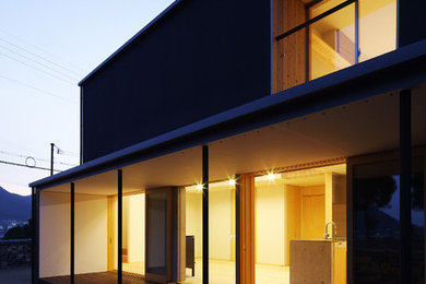 Cette photo montre une petite façade de maison marron moderne à un étage avec un toit en appentis et un toit en métal.