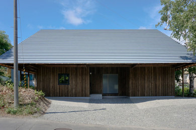 Ejemplo de fachada de casa marrón pequeña de dos plantas con revestimiento de madera, tejado a cuatro aguas y tejado de metal