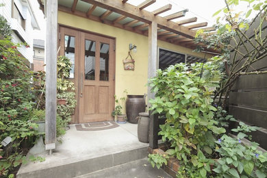 Imagen de fachada de casa amarilla asiática pequeña de dos plantas con tejado de un solo tendido y tejado de metal